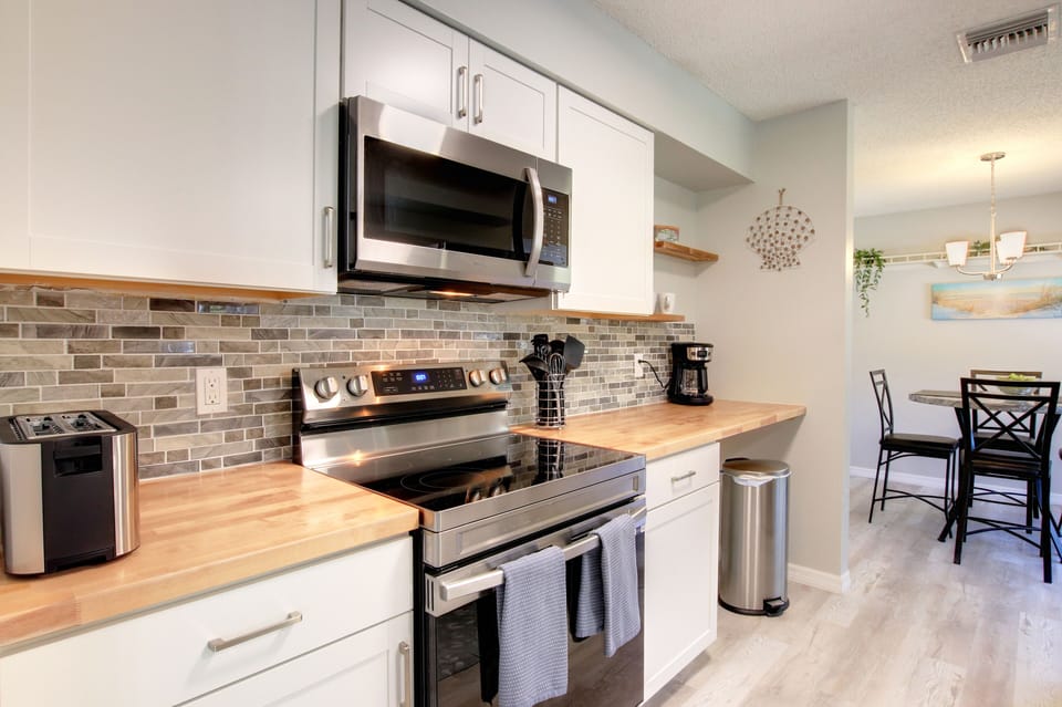 Kitchen stovetop/oven, microwave and coffee station.