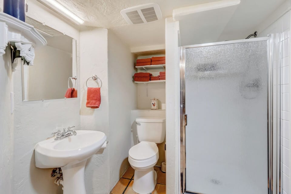 Bathroom adjoining main living area with shower, sink, toilet and towels 