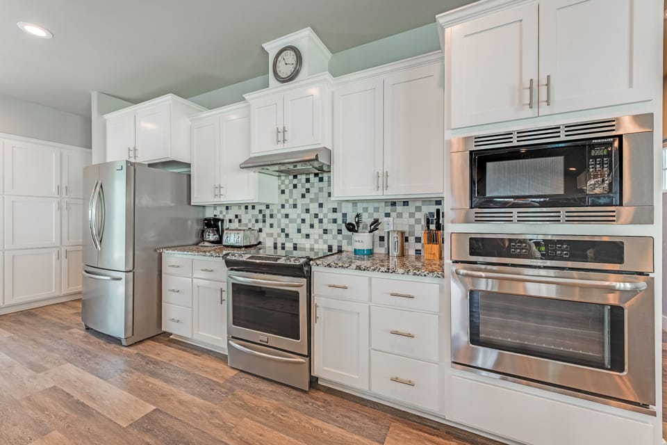 Cook with ease in this fully-equipped kitchen featuring stainless steel appliances, granite counters, and crisp white cabinetry perfect for your culinary adventures.