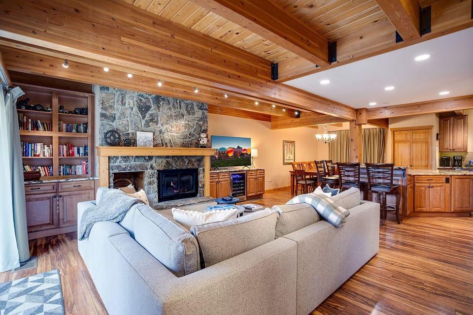 Unwind in your spacious open-concept living area with vaulted wood ceilings, stone fireplace, and flowing kitchen space perfect for gatherings.