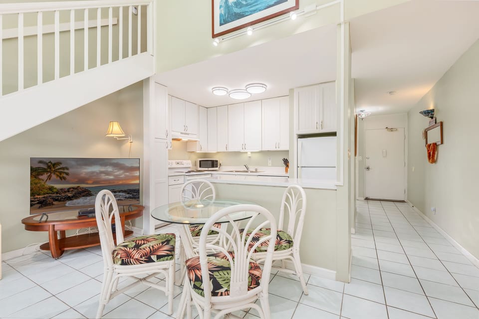 Charming kitchen and dining area with white cabinetry, tropical accents, and plenty of natural light.