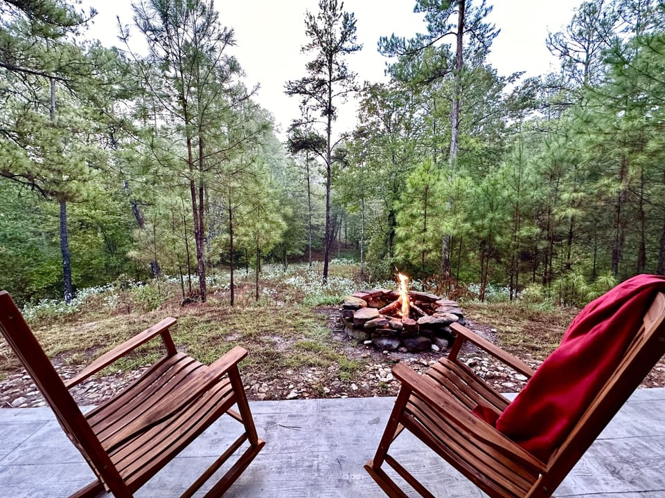 Hilltop patio has rocking chairs and a fire pit overlooking the pond below.