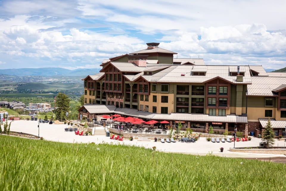 A scenic exterior shot of the hotel's outdoor terrace, with a grassy slope in the foreground and mountain views behind.