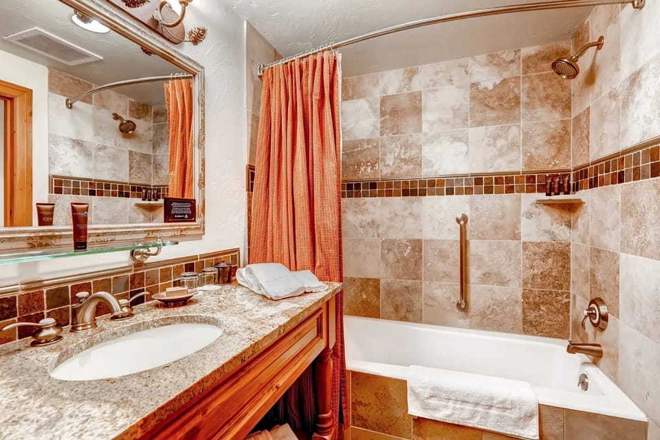The bathroom is modern and features luxe bath amenities and a shower-tub combination.
