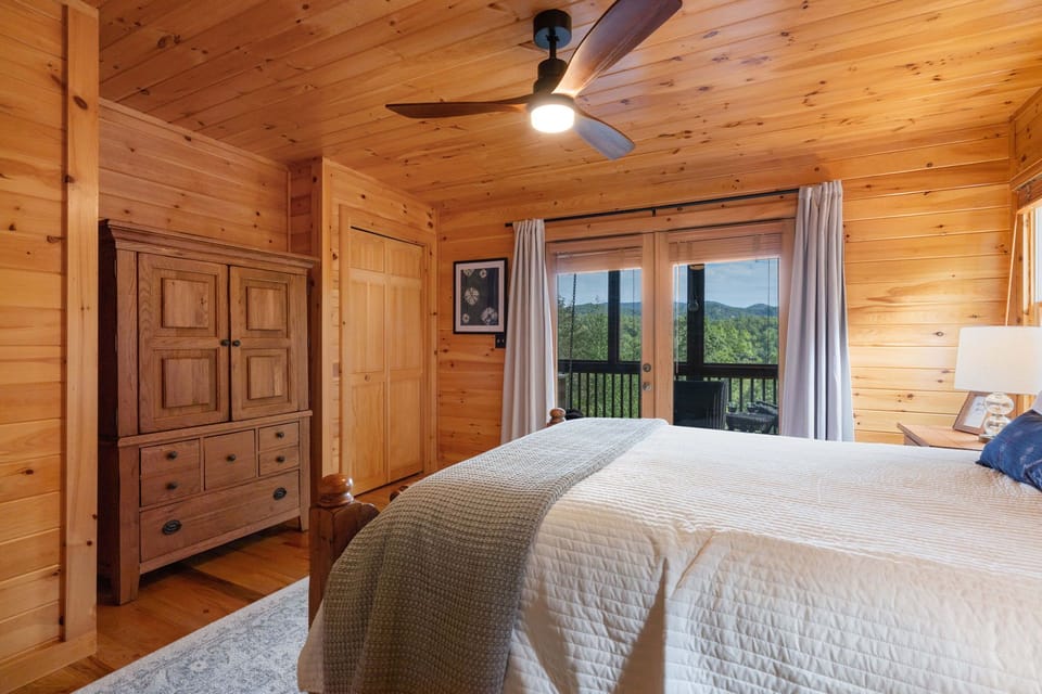 Main level bedroom offers a mountain view and opens to the screened porch outside. 