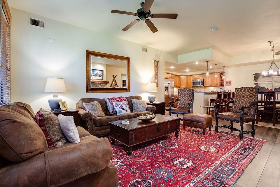 Sink into plush leather sofas in your warm living space, where rustic charm meets modern comfort beneath soaring ceilings.