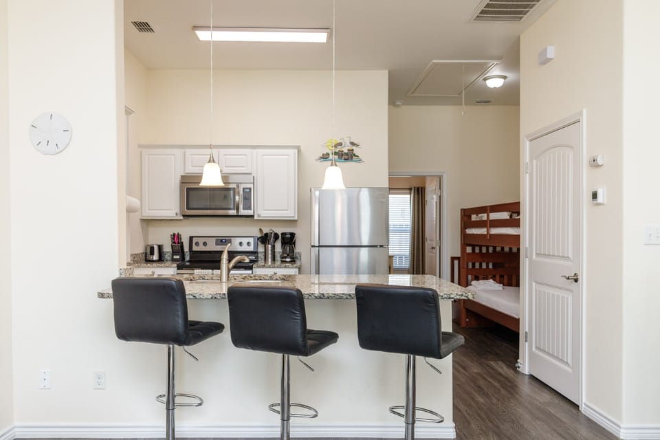 Your sleek modern kitchen features granite counters, stainless appliances, and a breakfast bar perfect for morning coffee or casual meals.