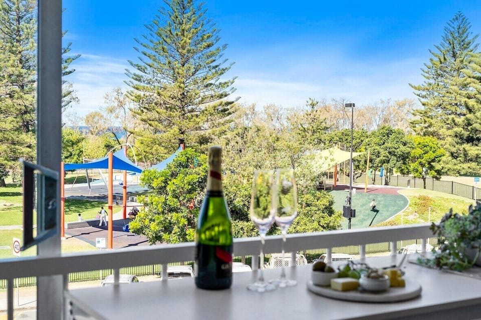 Balcony with bar stools, seating and ocean and park views across the road.