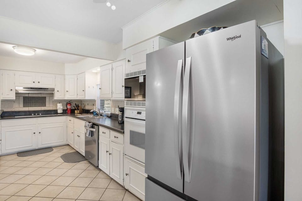 This efficient kitchen features crisp white cabinetry, modern appliances, and a handy breakfast bar that opens into the dining area, making it a perfect hub for home-cooked meals and conversation.
