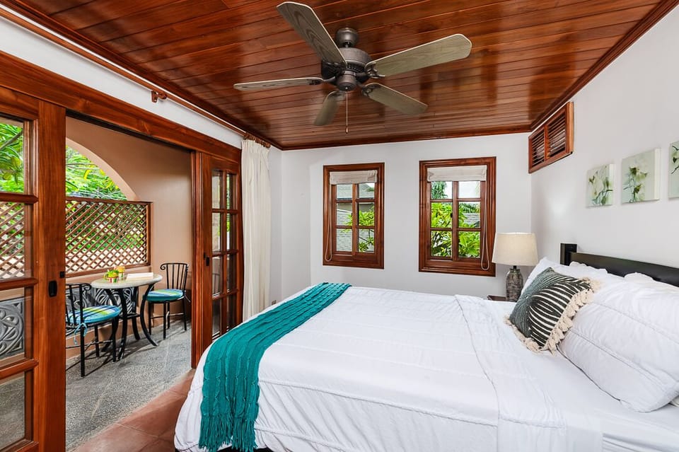 Master bedroom at the Langosta Beach villa in Tamarindo with king-size bed and private balcony featuring a cozy table and chairs. Perfect for relaxing, enjoying morning coffee, and a luxurious Costa Rica getaway.