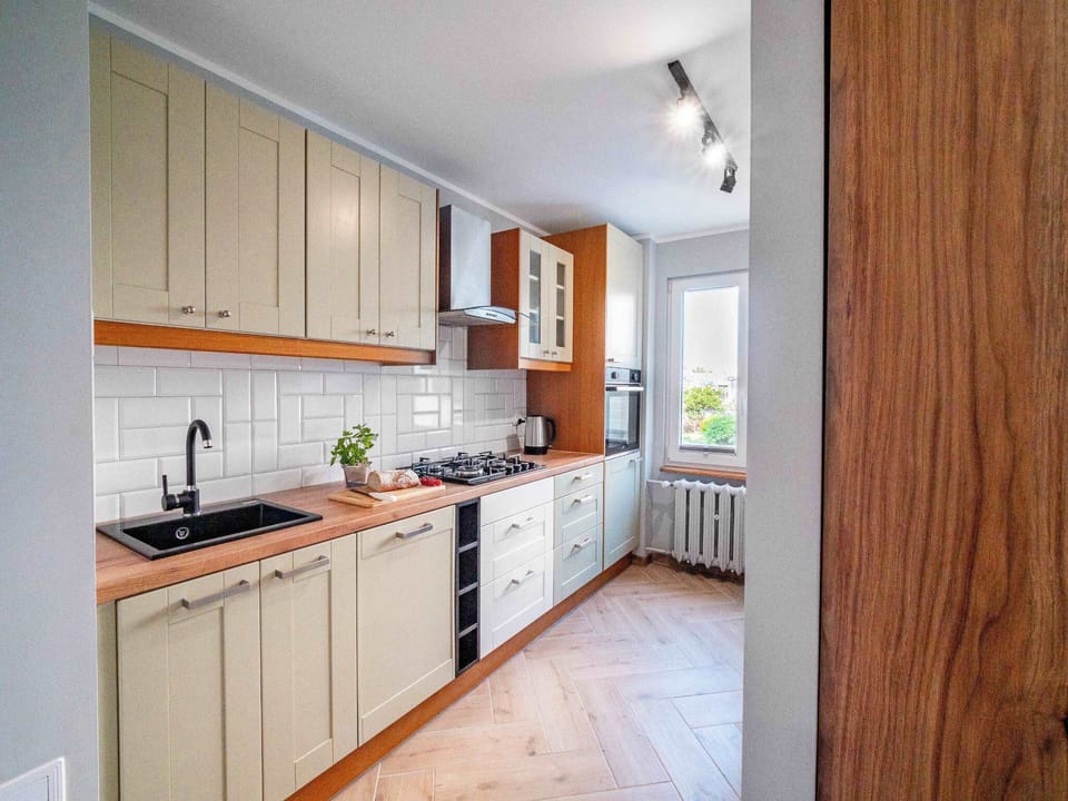 A modern kitchen with beige cabinets, wooden countertops, and plenty of space for cooking and storage.
