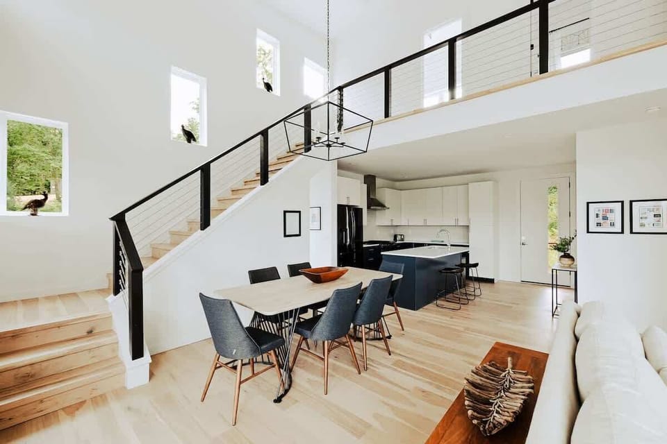 Dine beneath modern lighting with windows that frame forest greenery. Clean lines and natural textures meet thoughtful design.