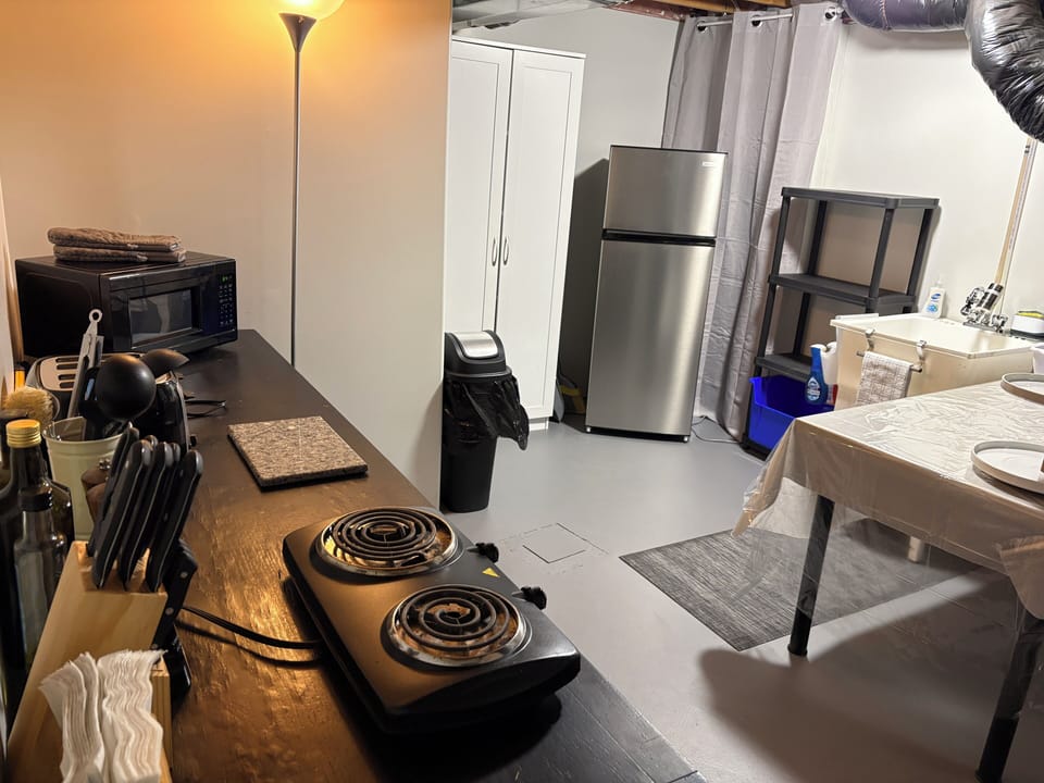 Fully equipped kitchenette with full fridge, hotplate, dishes, and food storage.