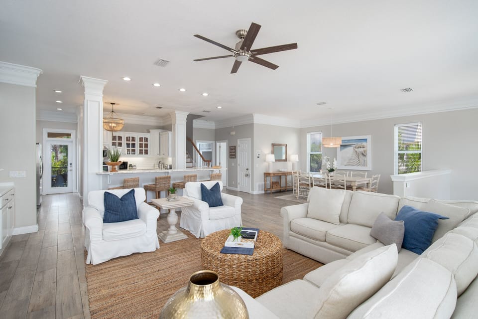 Your spacious open-plan living area invites relaxation with plush white sofas, natural textures, and coastal-inspired blue accents throughout.