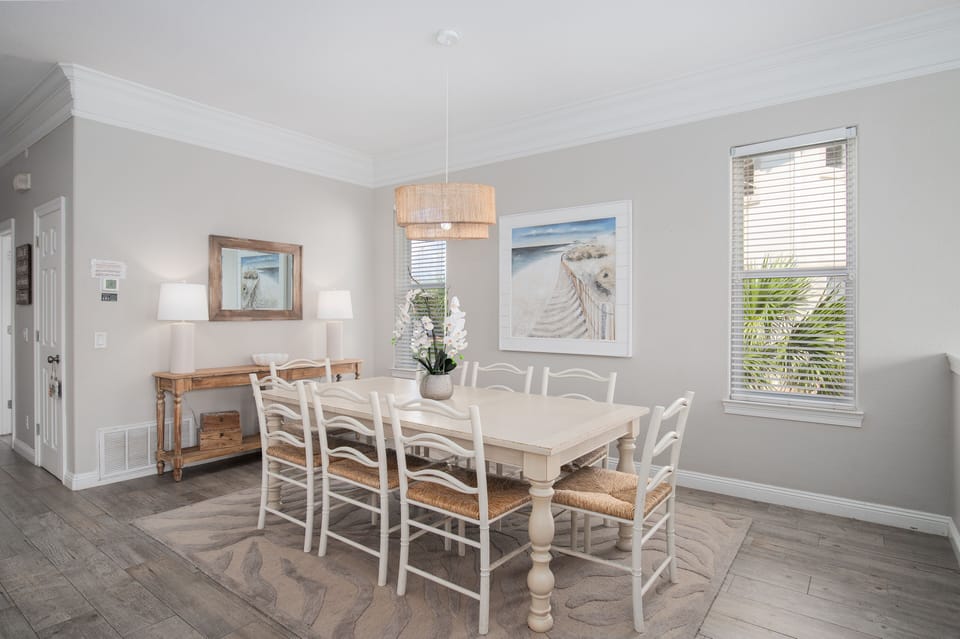 Gather around this bright dining space where coastal charm meets comfort. The elegant white table welcomes your group for memorable meals together.