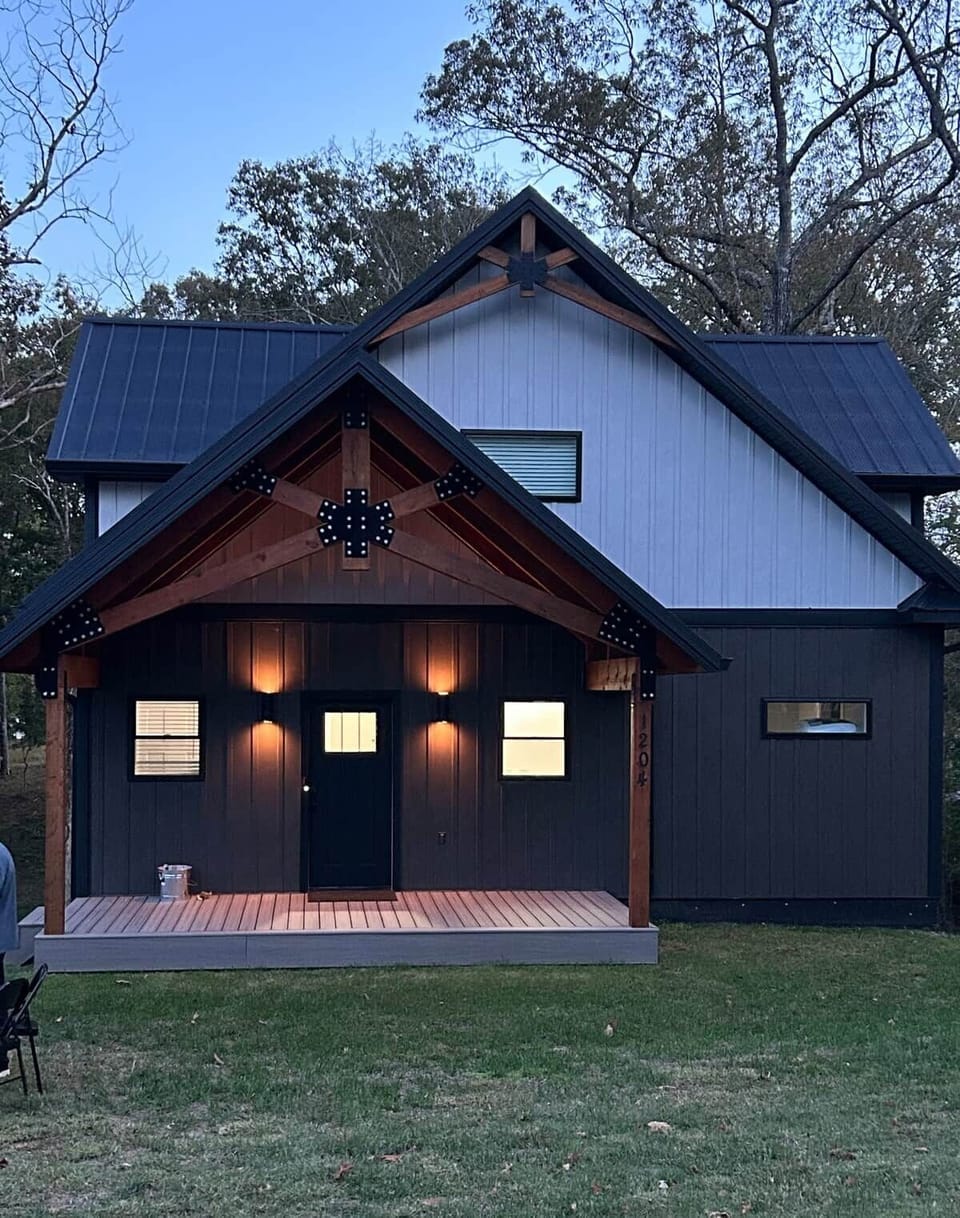 Modern cabin with timber porch & warm lighting in a quiet wooded setting