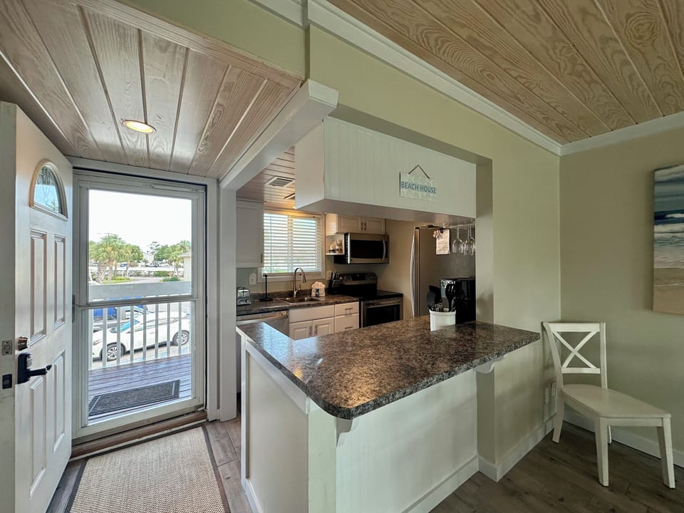 Your fully equipped kitchen awaits with granite counters and stainless appliances, perfect for preparing coastal meals while enjoying natural light.