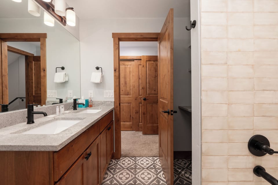Unwind in your spacious bathroom featuring dual vanities, elegant patterned floors, and a luxurious walk-in shower with beautiful tile work.