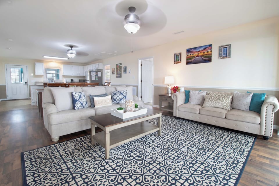 Sink into plush sofas in your spacious living room where coastal blues meet modern comfort, perfect for unwinding after beach adventures.