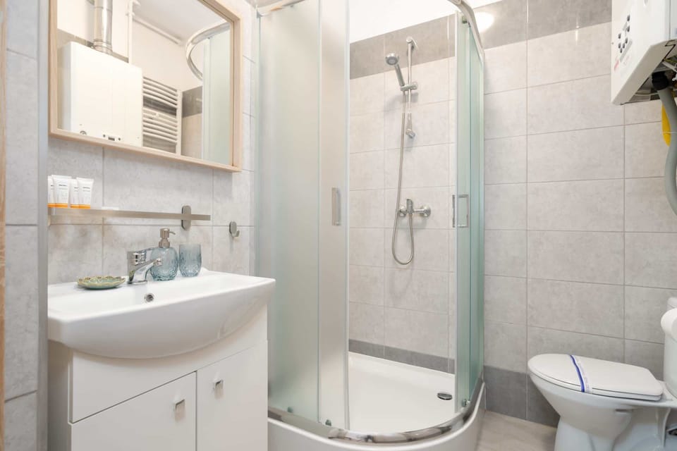 A modern bathroom with a glass-enclosed shower, white vanity, and tiled walls, offering a clean and elegant design.
