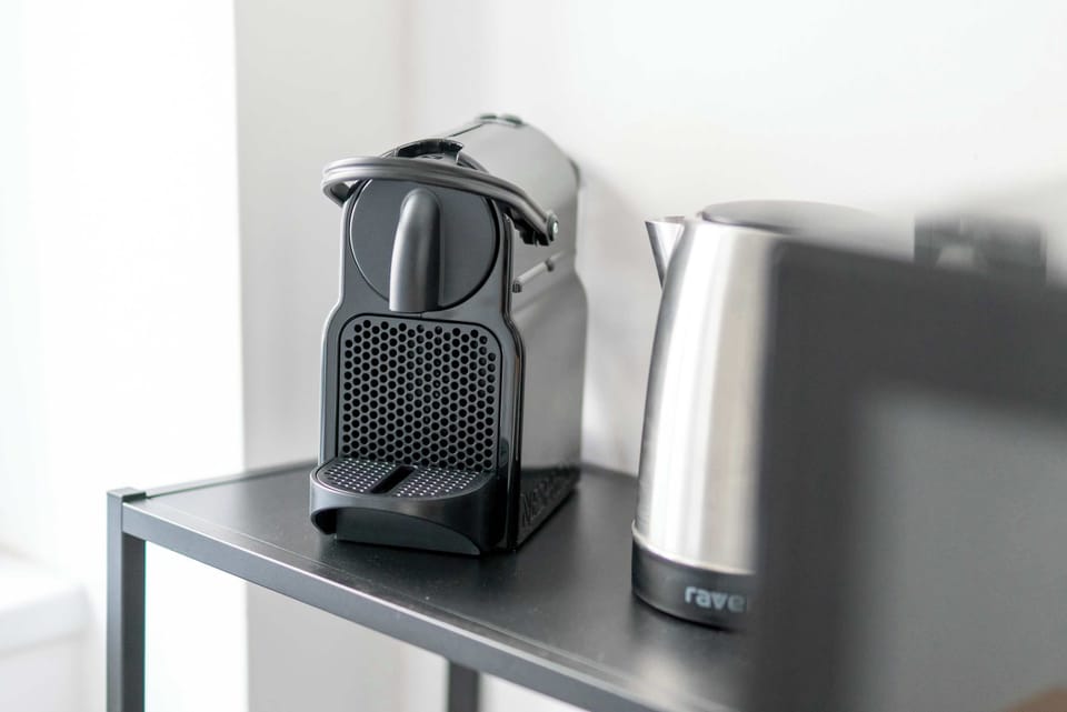 A close-up displays a coffee machine and kettle placed neatly on a countertop. Small appliances are arranged for convenience.