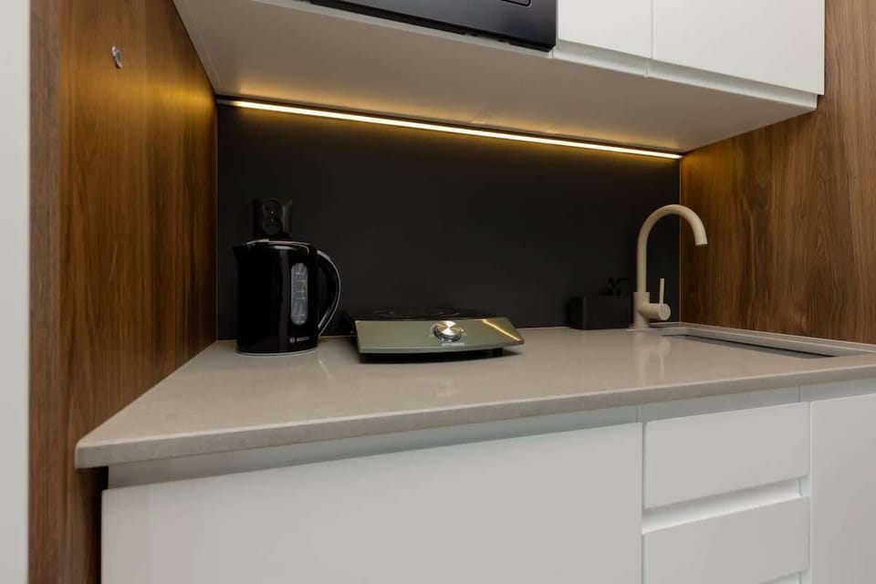 A sleek kitchen corner with white cabinets, a black countertop, and modern appliances, blending functionality with style.
