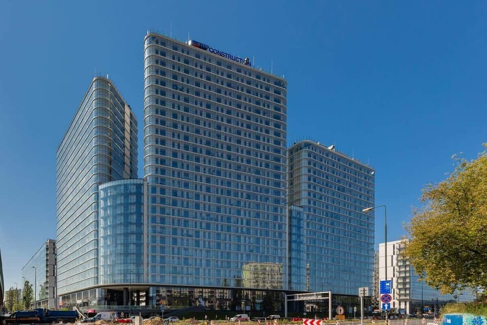 An exterior view of the apartment complex with contemporary design, featuring tall glass buildings and a polished finish.
