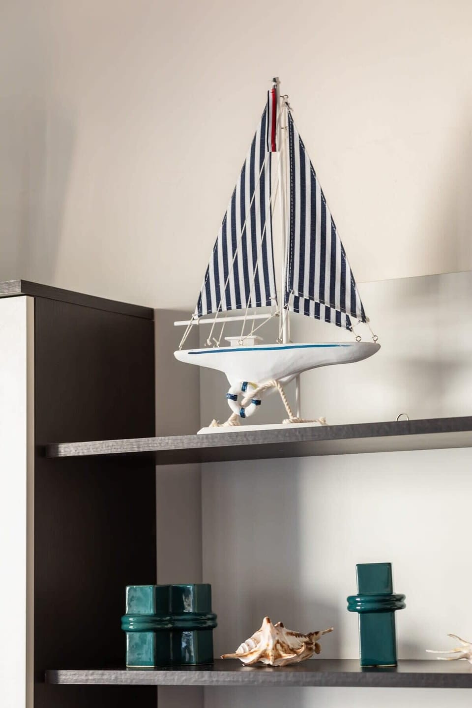 A decorative shelf with beach-inspired accents, including a striped lamp and teal vases, adding character to the room.

