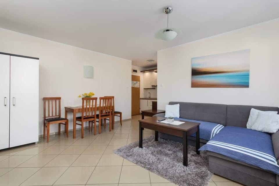 Another view of the living and dining area, showcasing its spacious layout, wooden chairs, and tiled flooring.