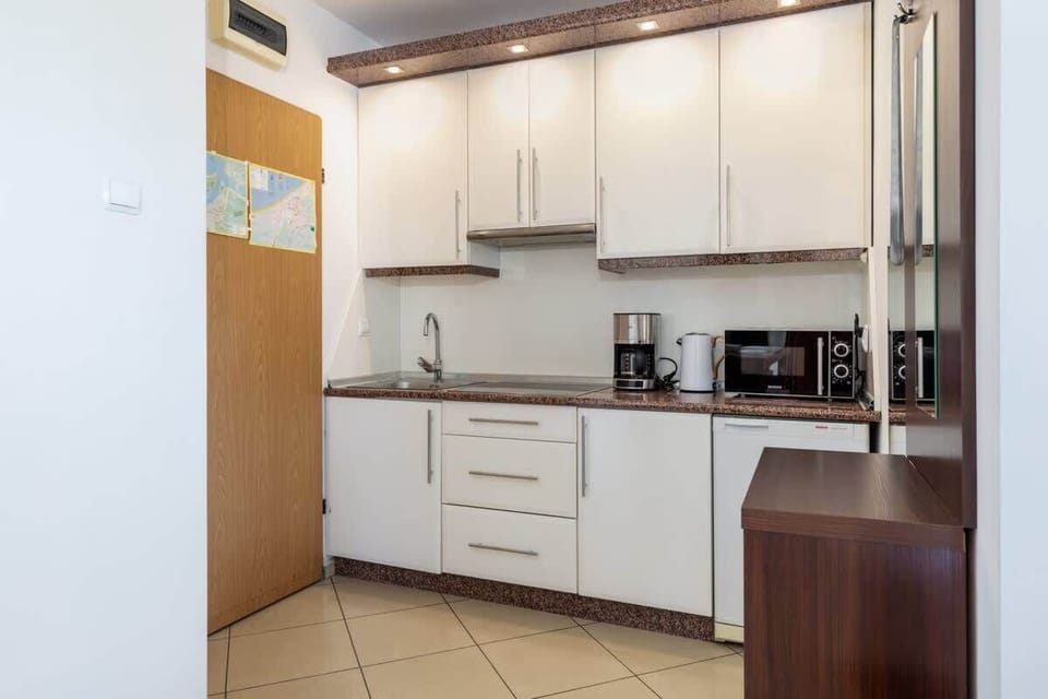 A modern kitchen with white cabinets, tiled floors, and appliances, creating a functional cooking area.
