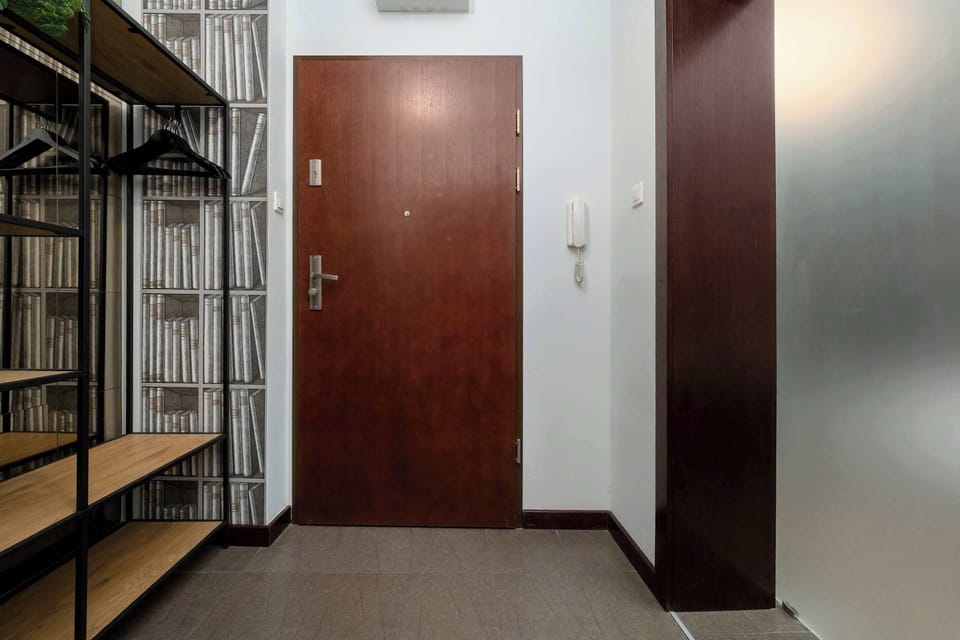 An entryway area with wooden doors and a shelving unit. The space looks practical for storage and daily essentials.