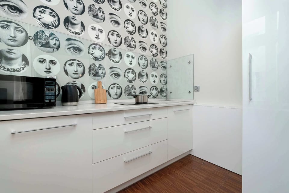 A bright kitchen space with glossy white cabinets and decorative wall art. The layout appears compact yet efficient for everyday use.