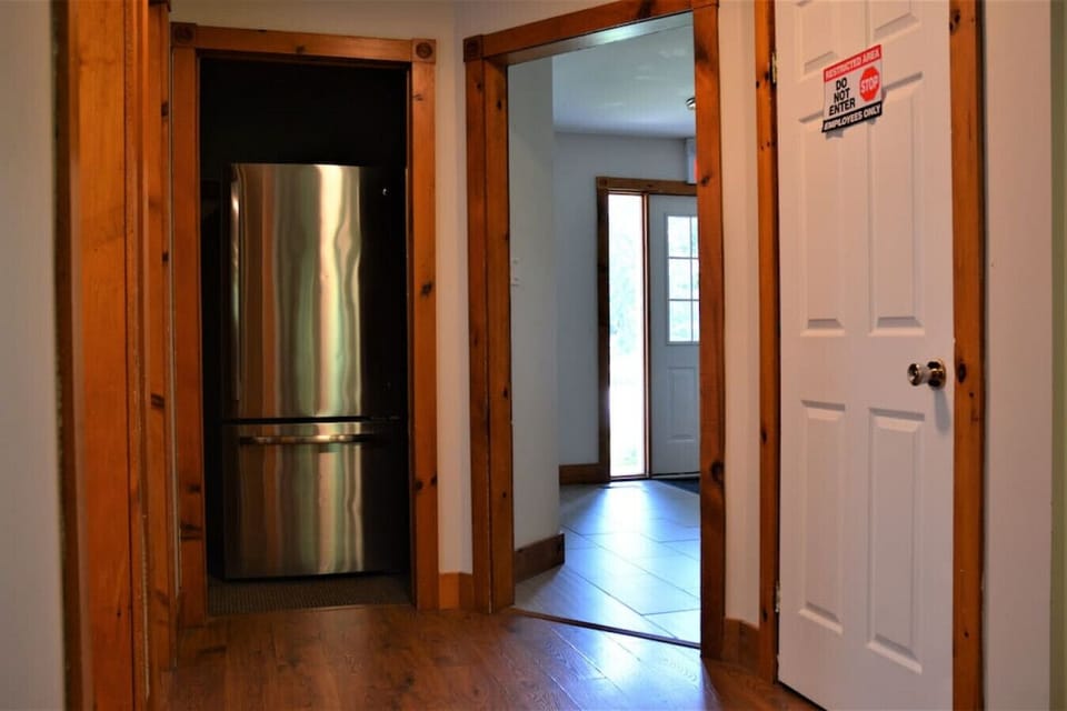 Main floor hallway facing an extra fridge and the front entryway