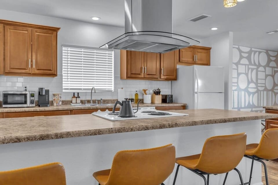This kitchen island, featuring a sleek stove top as its centerpiece and bar seating for four, effortlessly blends functionality and socializing in the heart of the home.