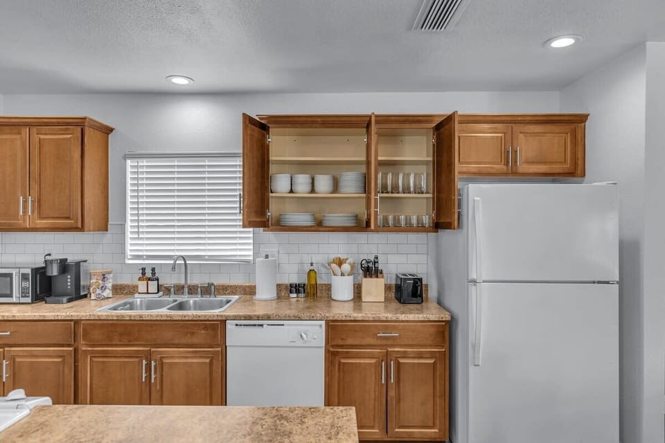 Culinary possibilities abound in this meticulously equipped kitchen, where every tool and gadget awaits your creative touch. With fully stocked cupboards and an array of dining wares, it's a gourmet's haven ready for any culinary adventure.