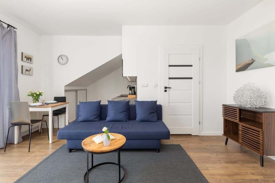 Another perspective of the living room showcasing a blue sofa, wooden accents, and a round coffee table for a cozy and stylish look.
