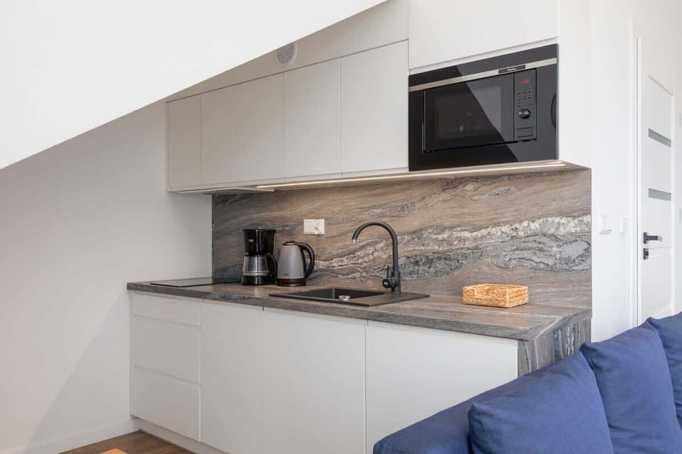A compact kitchen with white cabinets, a gray backsplash, and modern appliances, designed for practicality and style.
