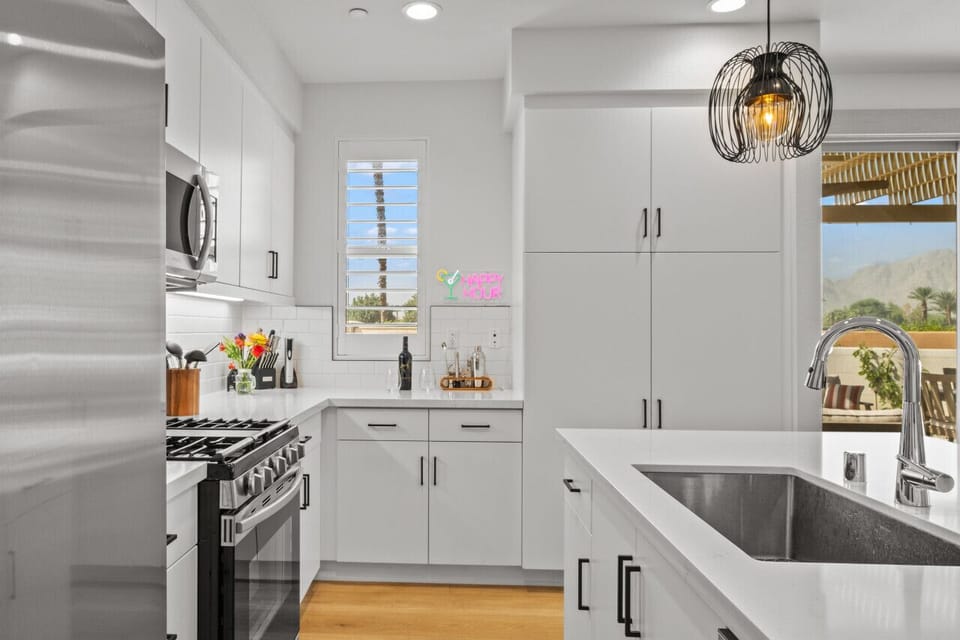 Bright modern kitchen w/ stainless steel appliances & crisp white cabinetry.