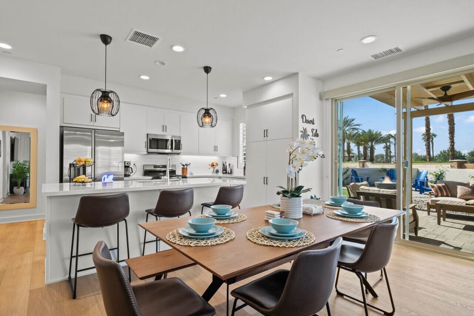 Gather around the elegant dining table set beside a bright, modern kitchen.
