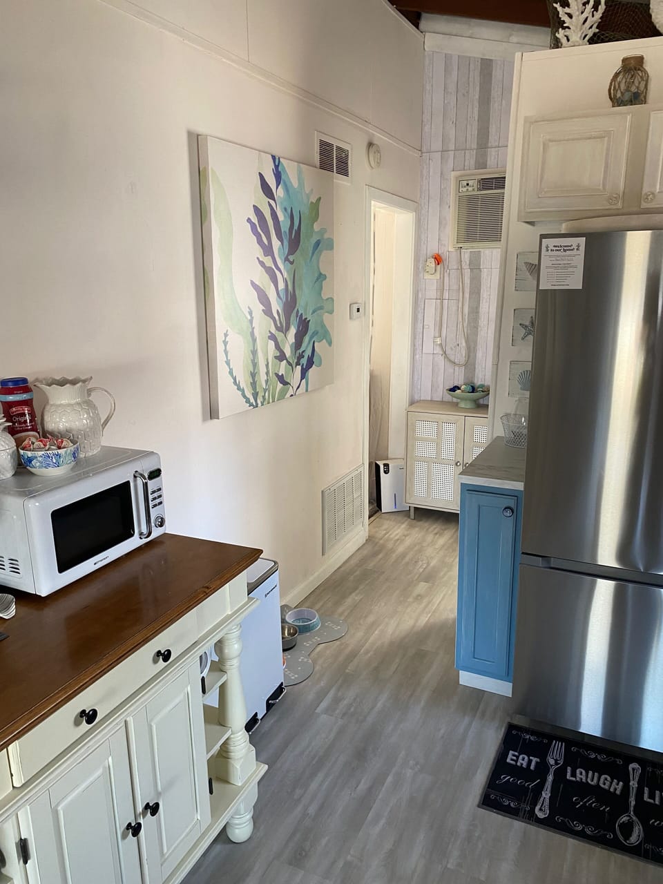 Microwave and kitchen storage cabinet. Hall leads to bathroom & laundry room
