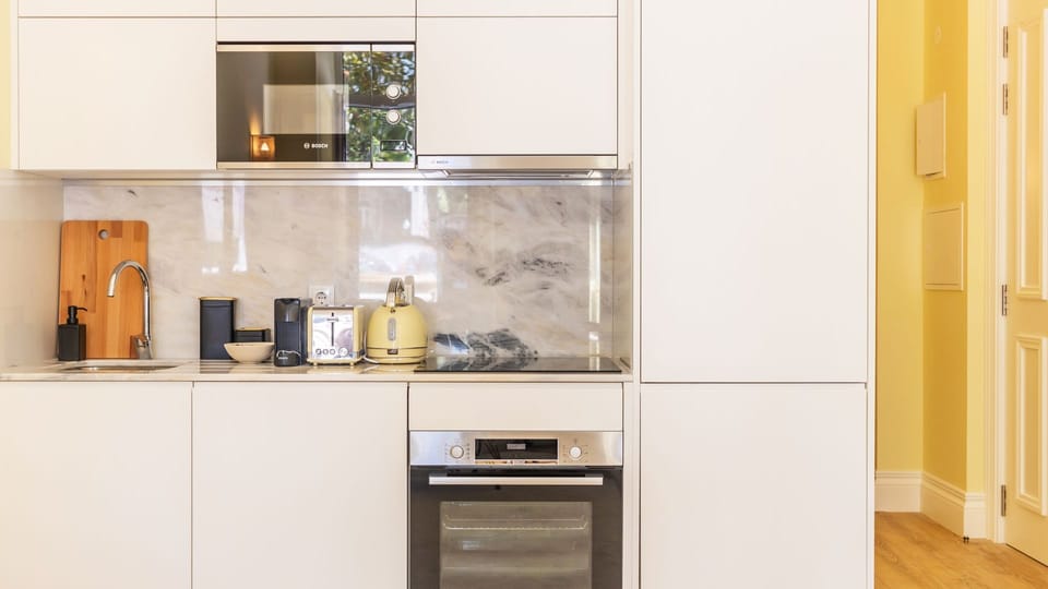 Unleash your inner chef in this well-appointed kitchenette, featuring modern integrated appliances like an oven, microwave, and stovetop to make meal preparation a breeze. With a sleek marble backsplash and essential tools like a toaster and kettle, culin