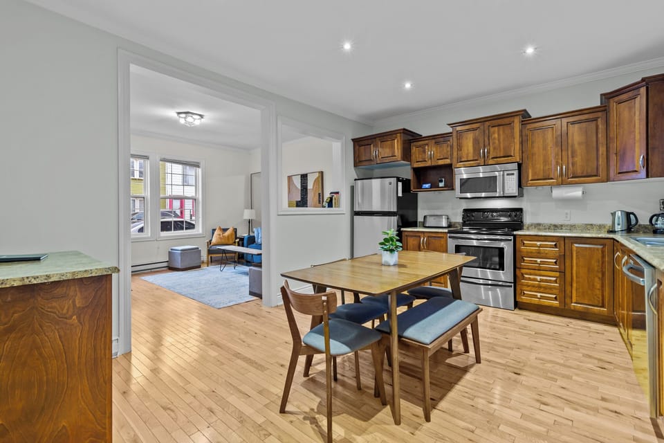 
The kitchen and dining area flows seamlessly from the living room, creating an open, interconnected space featuring modern appliances all arranged for efficient use. 
Adjacent to the kitchen is a cozy dining area, furnished with a table that comfortably sits several people, perfect for family meals or gatherings.