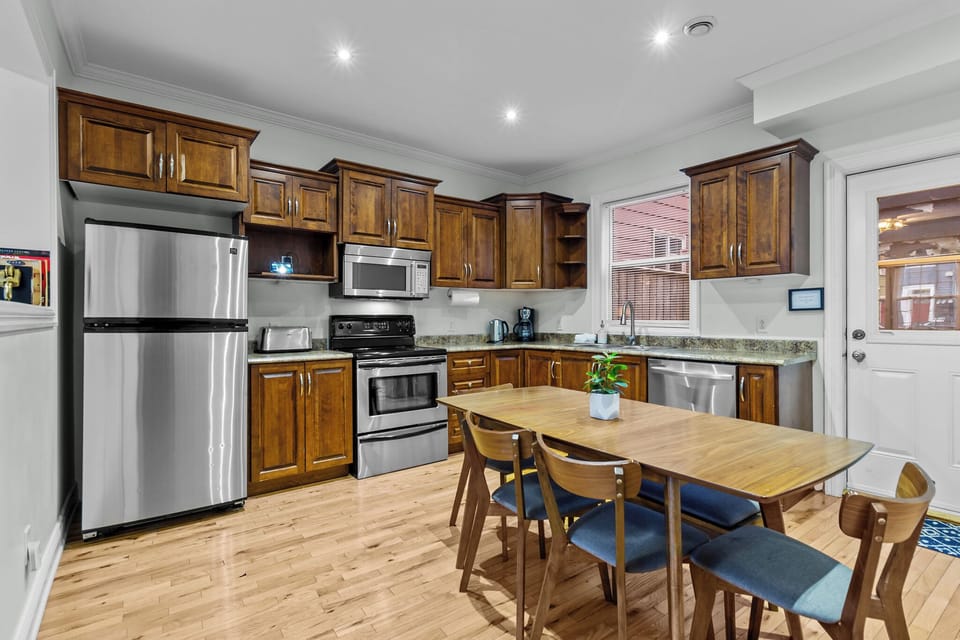 The kitchen is fully equipped with modern amenities, including a large refrigerator, stove, oven, microwave, and dishwasher.  Sleek countertops offer ample prep space, while stylish cabinets provide plenty of storage. Adjacent to the kitchen, a dining table is set for family meals or gatherings, creating a seamless flow between cooking and dining areas. The space is both functi...