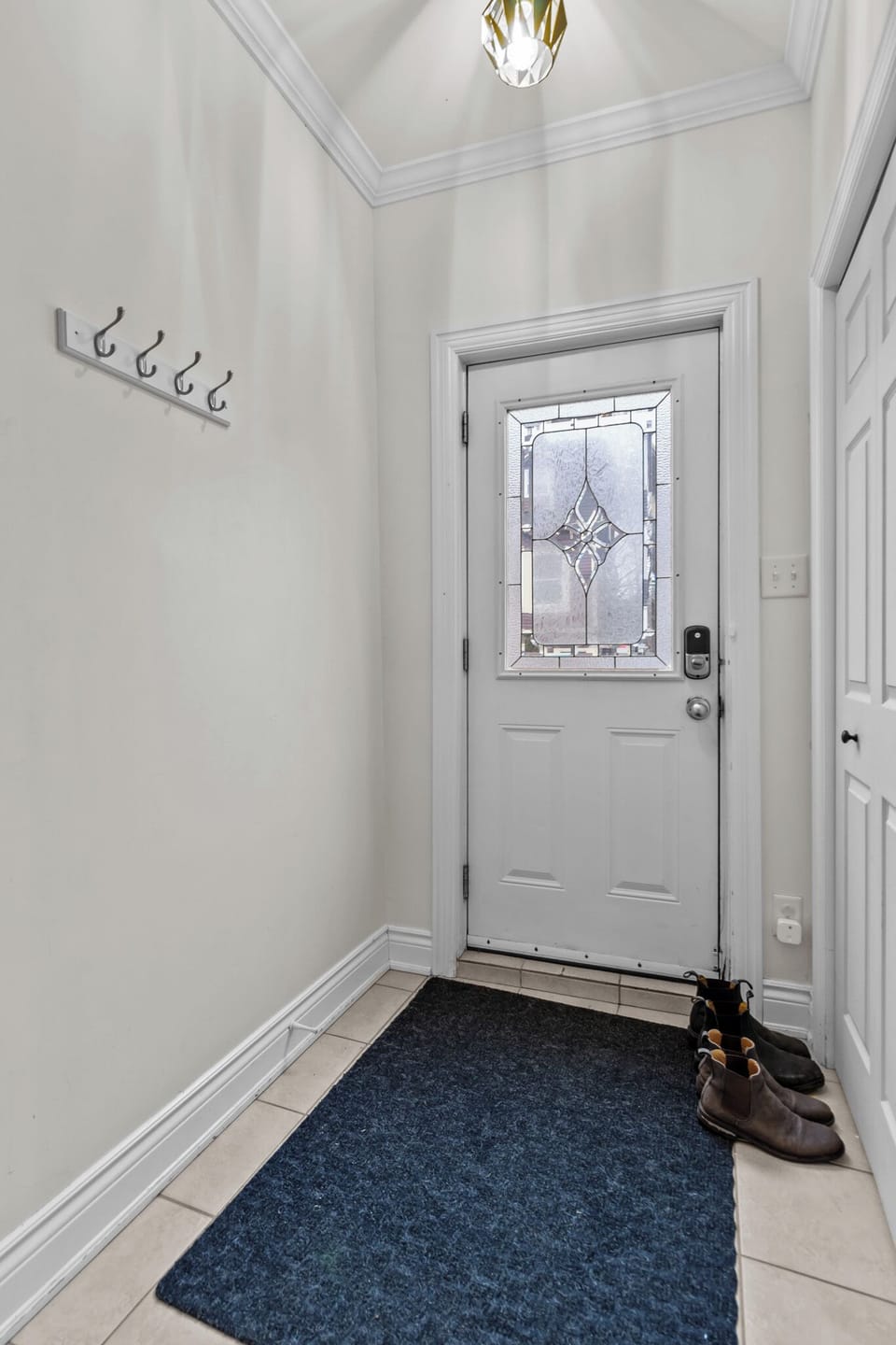 The entrance door opens into a small, functional space designed for convenience. A compact area is dedicated to storing shoes or hang important things like keys, coats, bags, or hats, and even parking pass. The area is well-lit  providing a practical solution for keeping everyday items in order as you enter or exit the home.