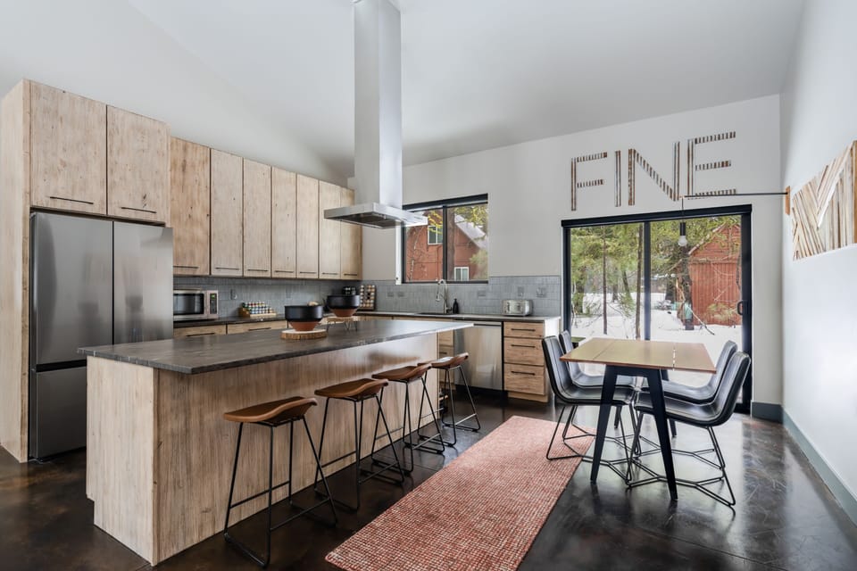 Leather chairs at minimalist solid oak dining table, Andrew Neyer crane light