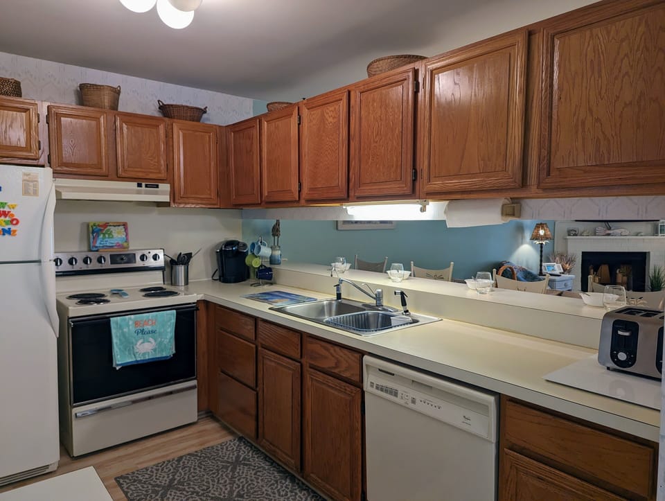 726 Bayberry Circle - Full Kitchen Overview - Functional kitchen featuring warm wood cabinetry, light countertops, and white appliances including a dishwasher and electric range.