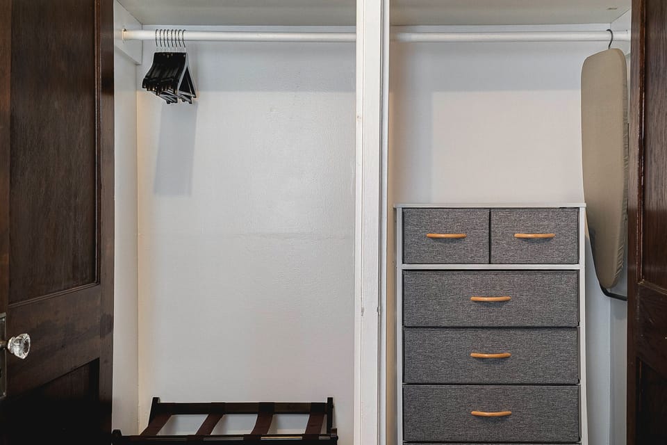 Large closet in the front bedroom with a dresser, hangers and luggage rack.