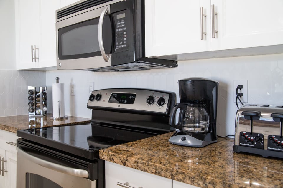 Full kitchen with electric stove, oven, dishwasher, coffee maker, fridge