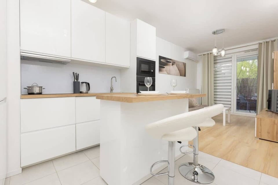 A modern kitchen with white cabinetry, wooden countertops, and an island with bar stools, blending functionality with style.
