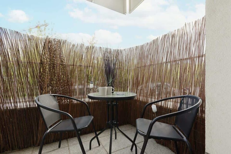 A private balcony with a small table and chairs, surrounded by decorative fencing, offering a serene outdoor seating area.
